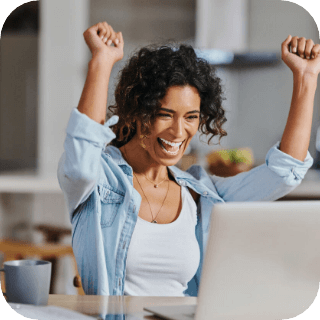 Woman cheering while looking at laptop