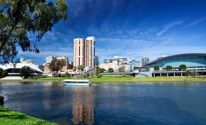 Adelaide city skyline with the River Torrens in the foreground on a sunny day.